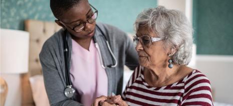 Home health aide supports elderly patient to stand