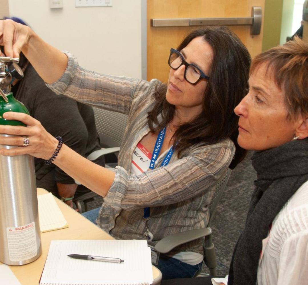 Two workshop participants check an oxygen tank's level.
